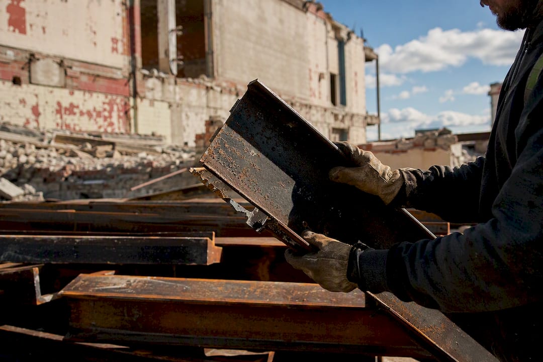 Worker inspecting salvaged steel beams