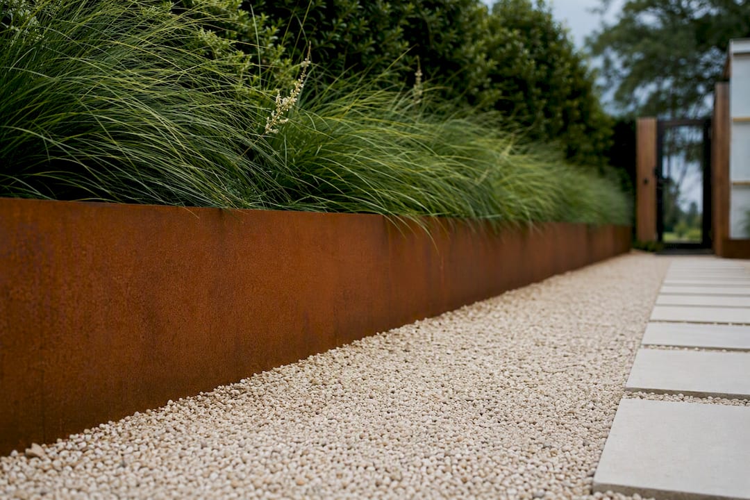 Corten steel accent wall beside greenery