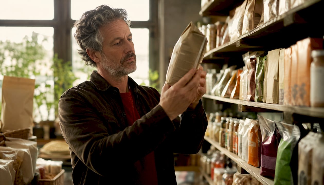 Shopper inspecting food label in grocery store aisle