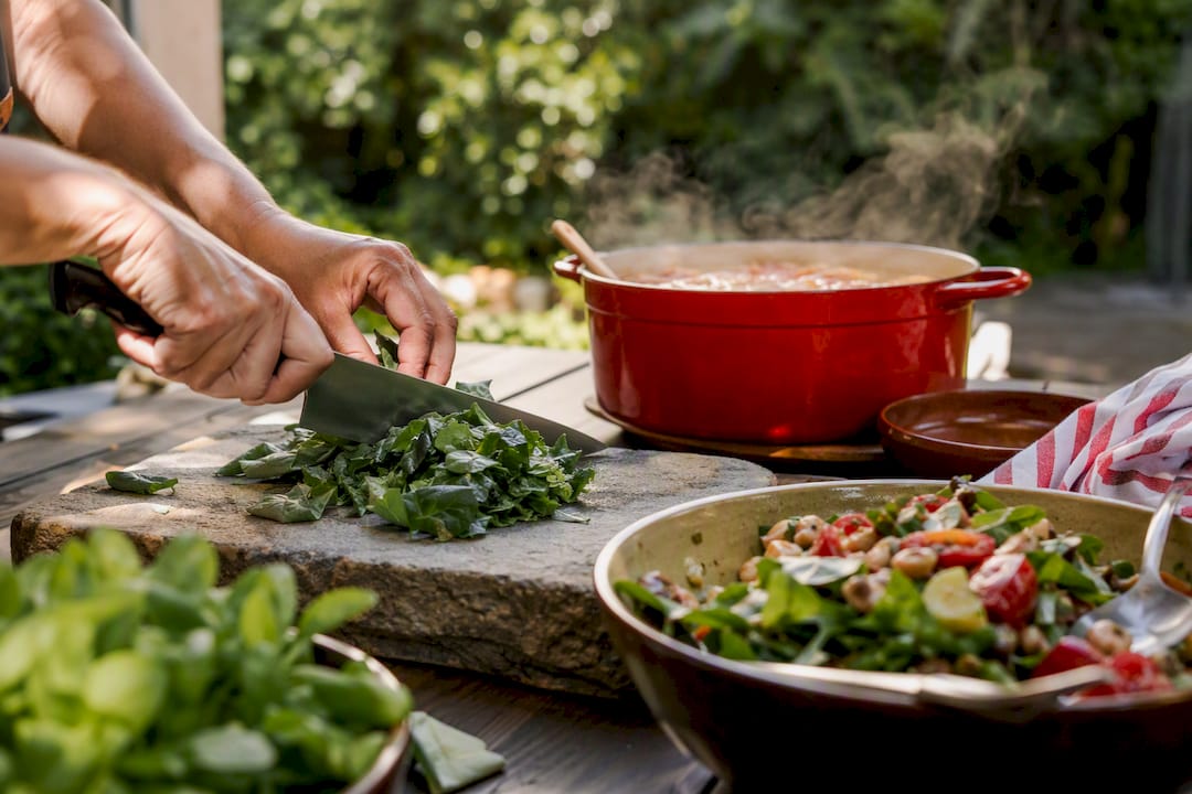 Hands chopping spinach with meal prep items