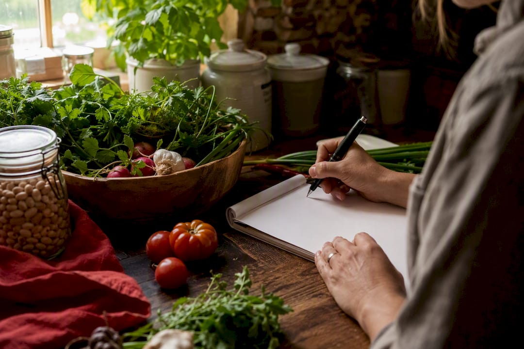 Hands updating pantry inventory next to grocery list