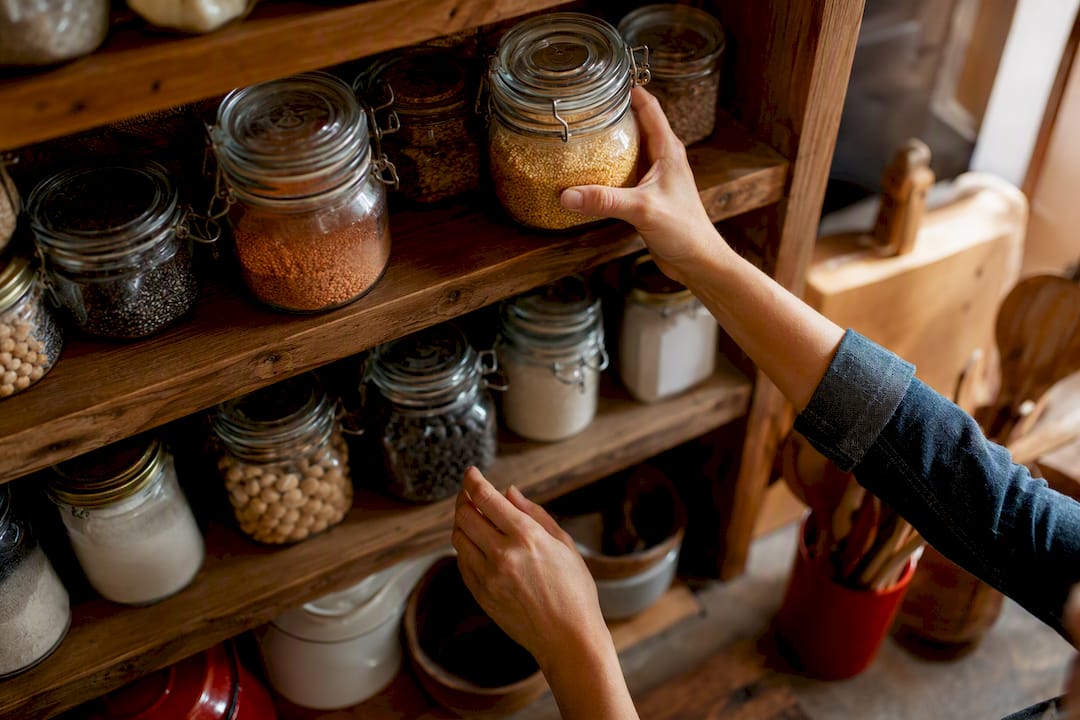 Hand organizing pantry shelf jars and cans