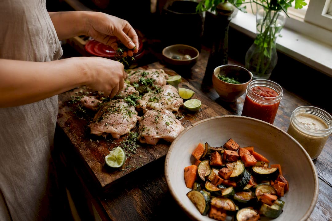 Hands chopping chicken and prep ingredients on kitchen counter