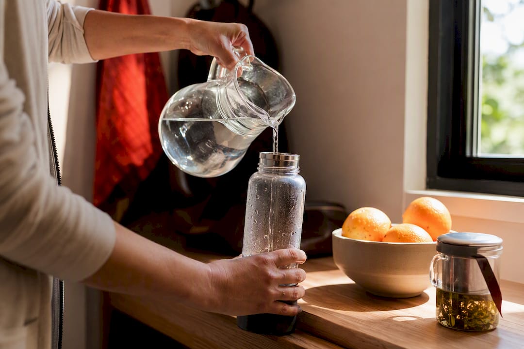 Hands refilling a reusable water bottle