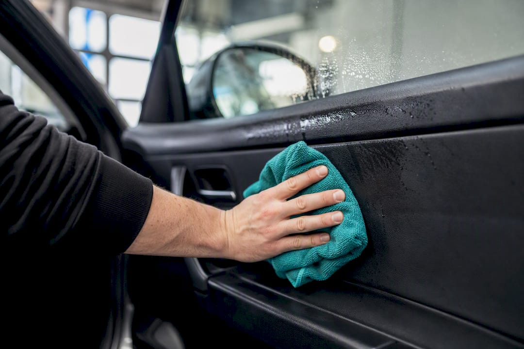 Hand cleaning car door panel with microfibre cloth