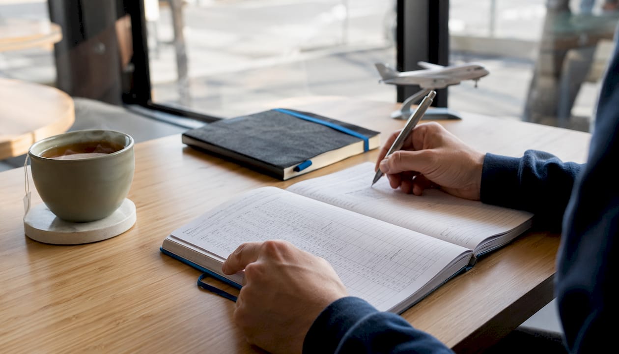 Hands writing in flight training logbook