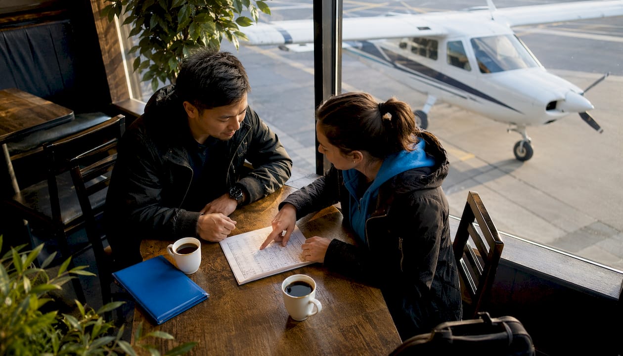 Two pilots reviewing preflight checklist outdoors