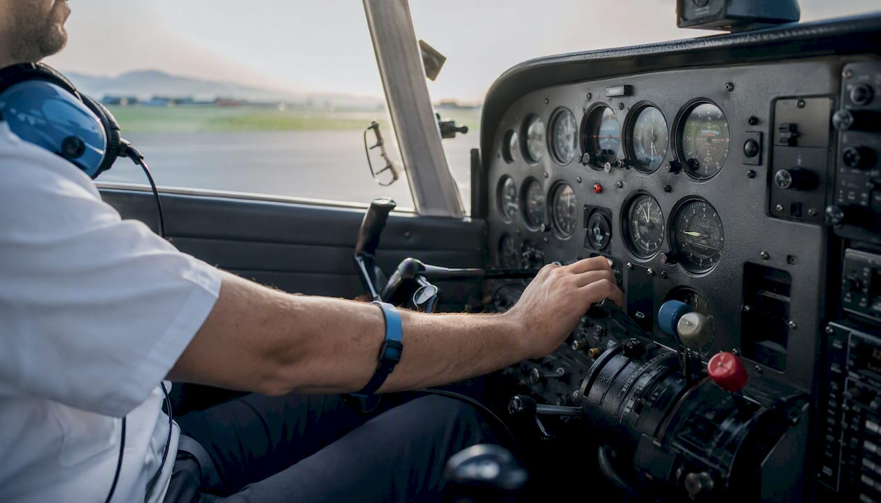 Pilot adjusting throttle with tachometer and Hobbs meter