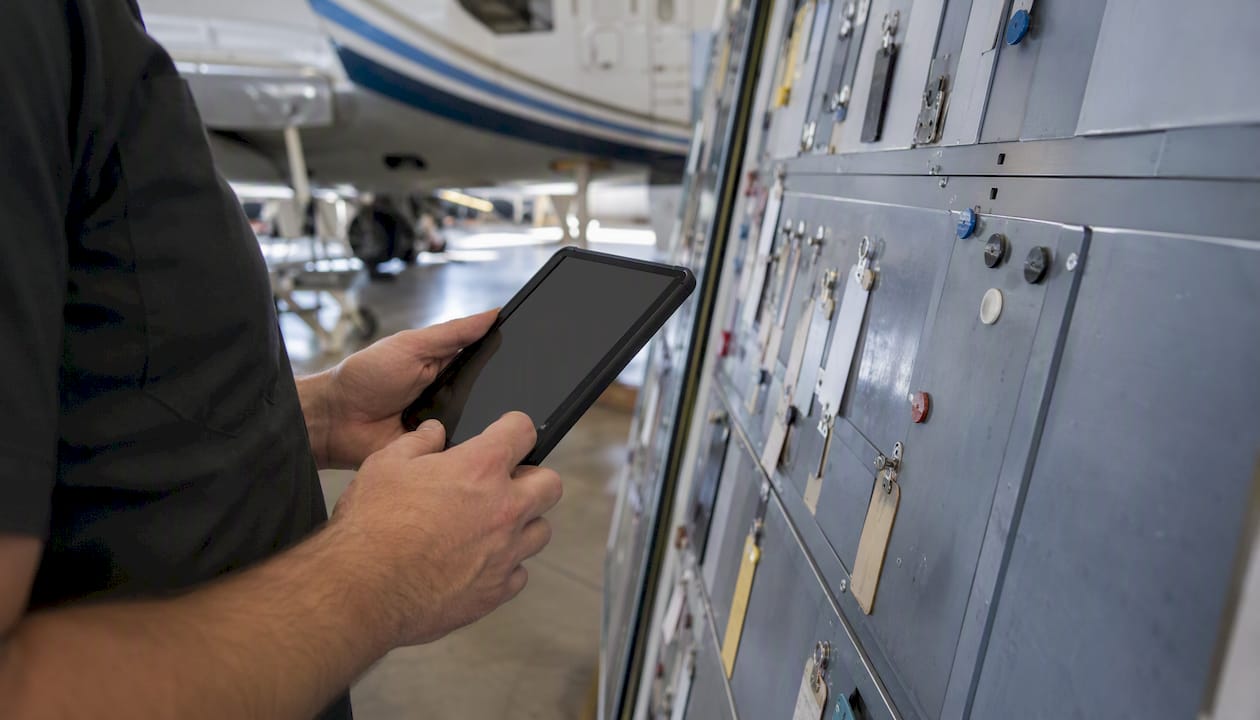 Technician hands with checklist device near maintenance board