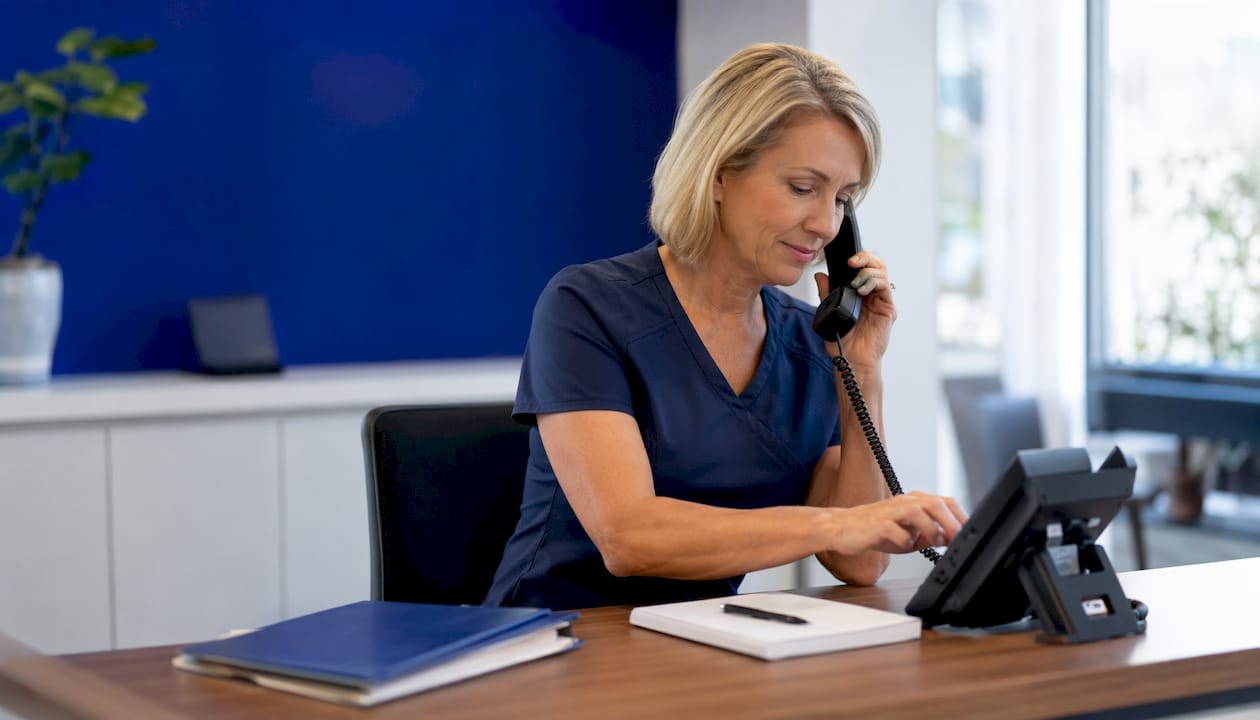 Close-up of hands using clinic phone for AI call