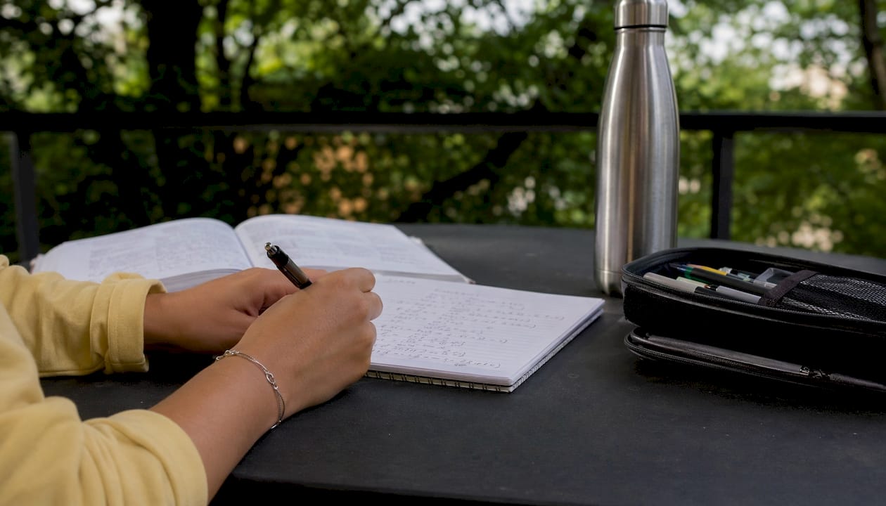 Hands writing calculus formulas in notebook