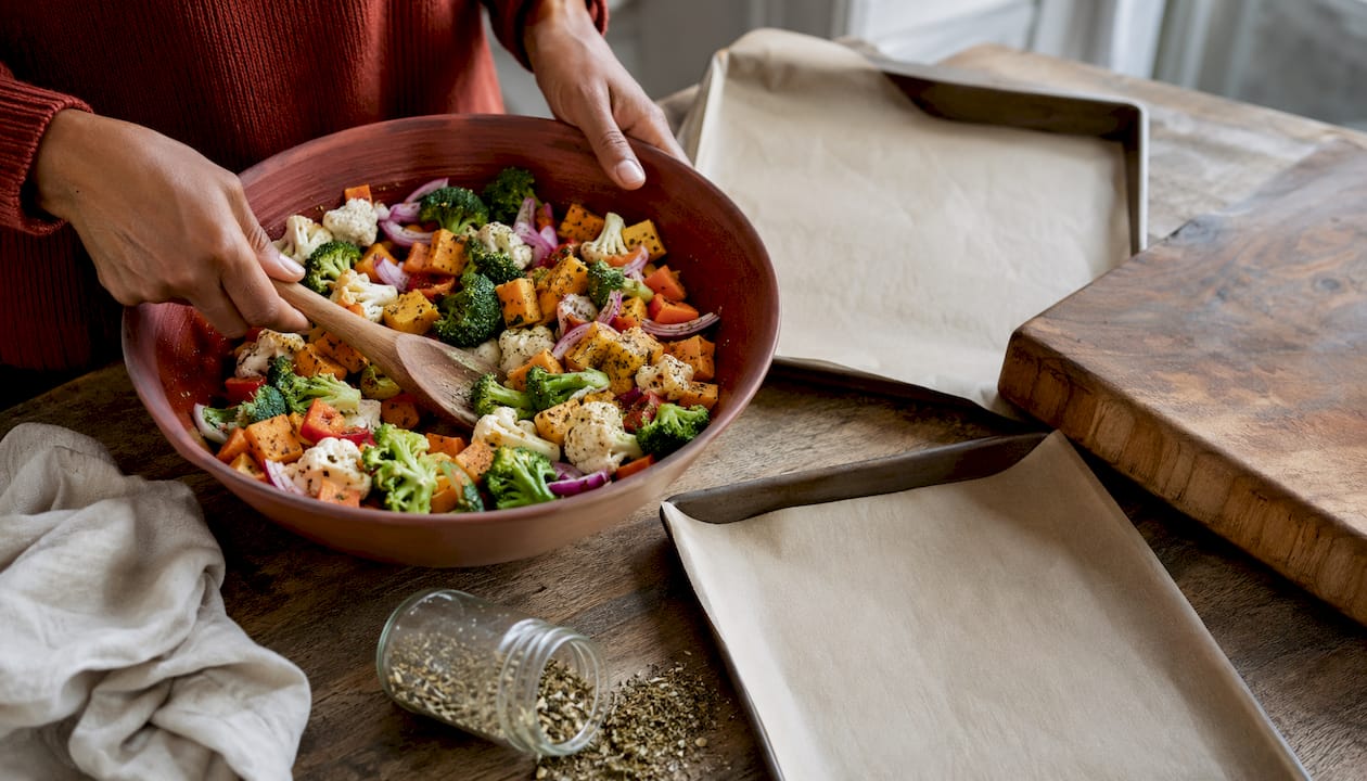 Hands tossing vegetables with kitchen tools