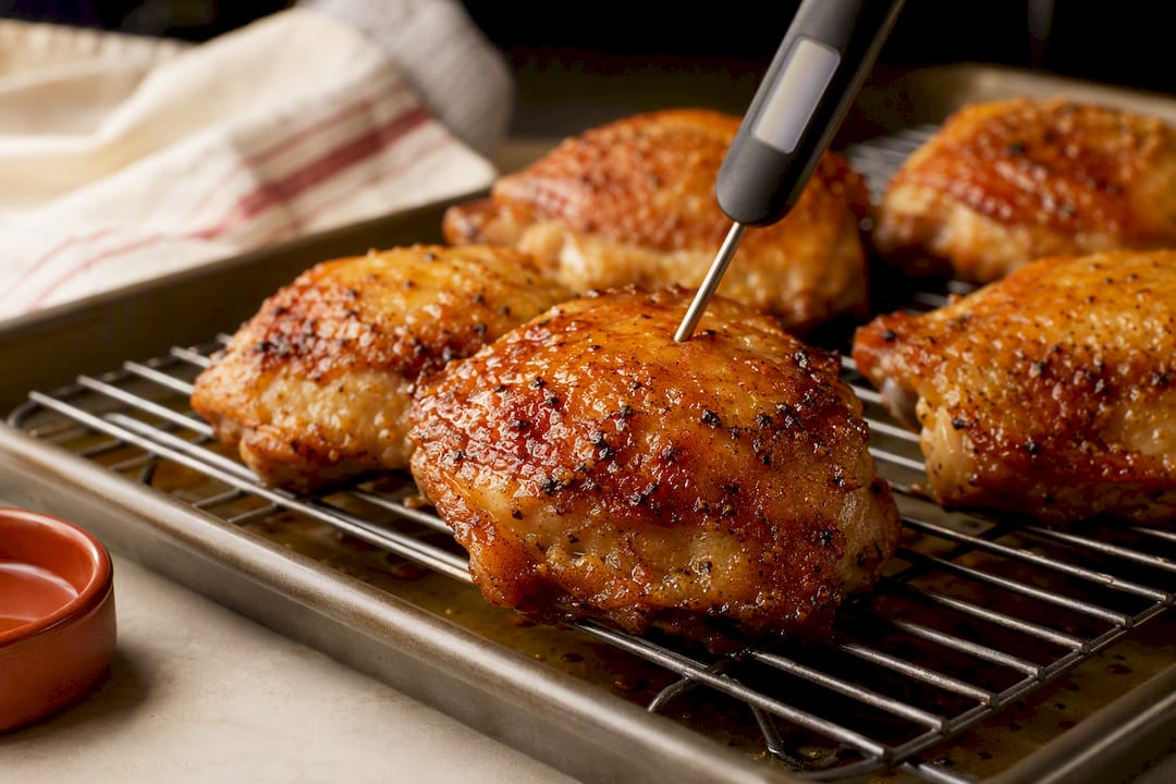 Cooked chicken thighs resting with thermometer