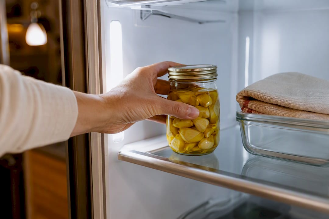 Jar of garlic confit entering refrigerator