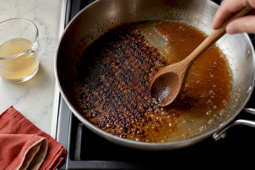 Wooden spoon loosening browned fond