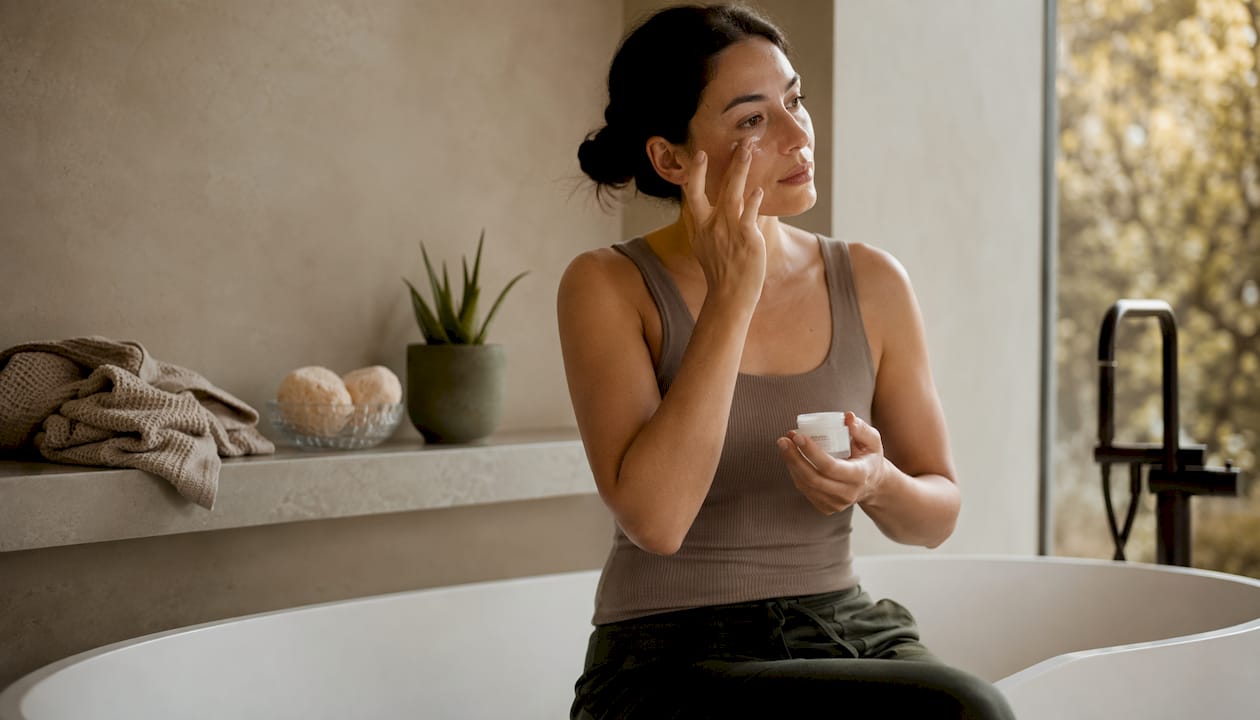 Side profile woman applying Hyaluronic Acid eye cream