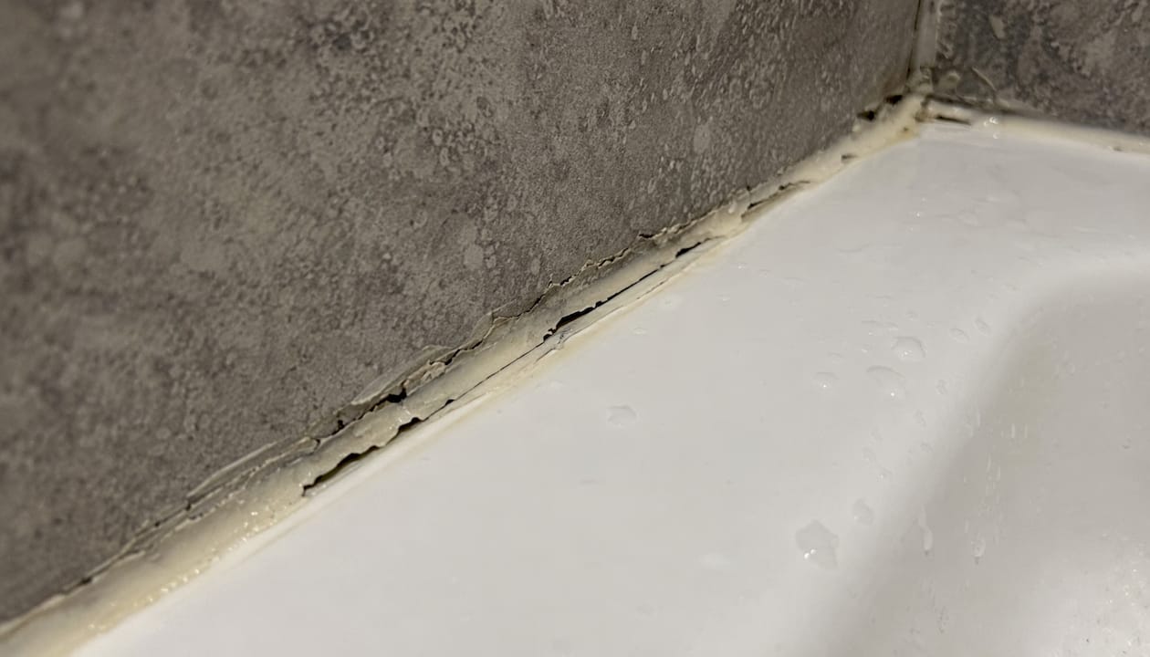 Close-up of failed silicone sealant on shower tray