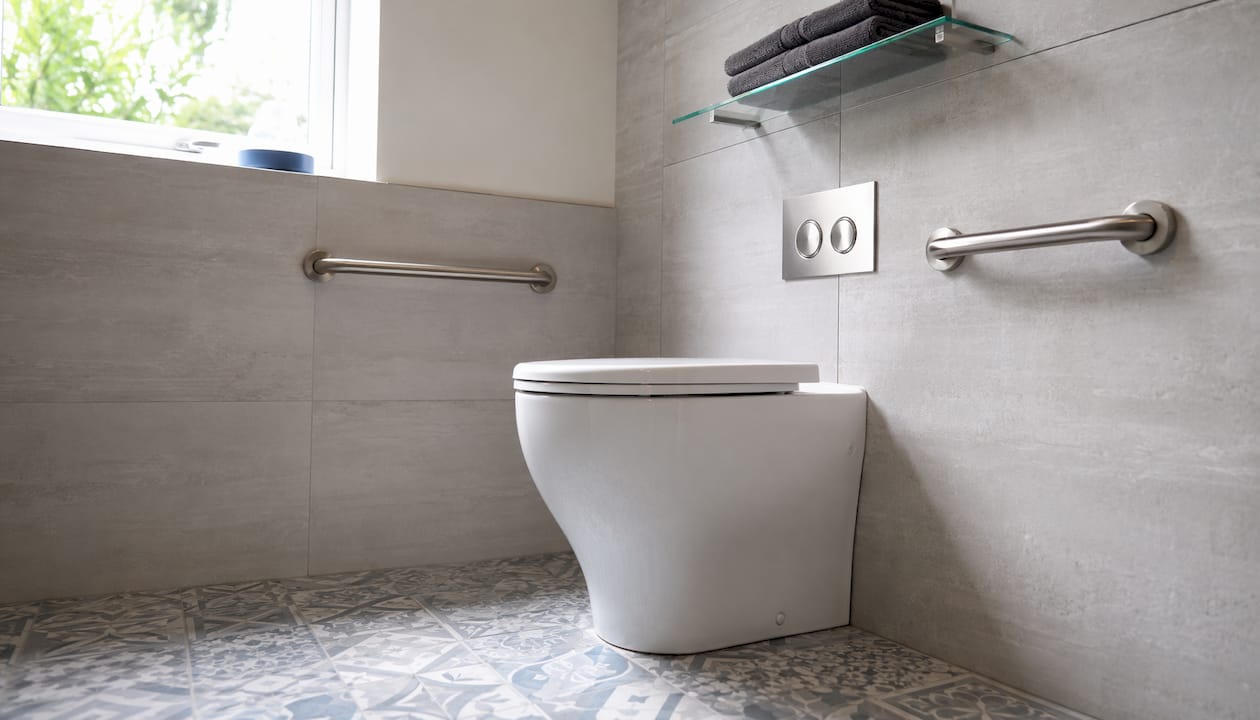 Comfort height toilet with grab rails in bathroom corner