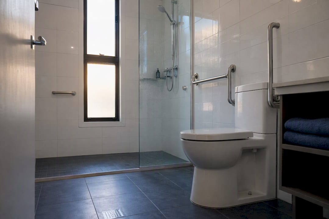 Accessible small bathroom with grab rails and walk-in shower