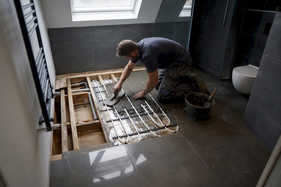 Plumber installing electric underfloor heating mat