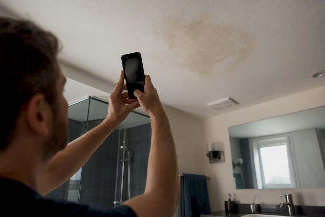 Hand photographing bathroom ceiling damp patch