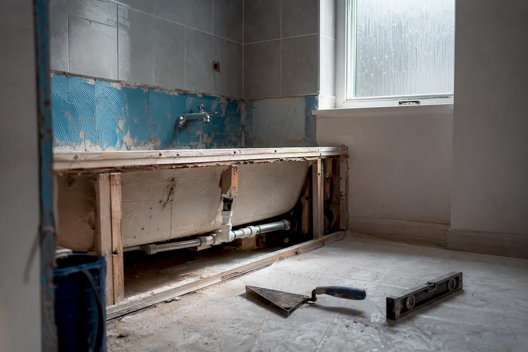 Bathroom mid-conversion with exposed plumbing