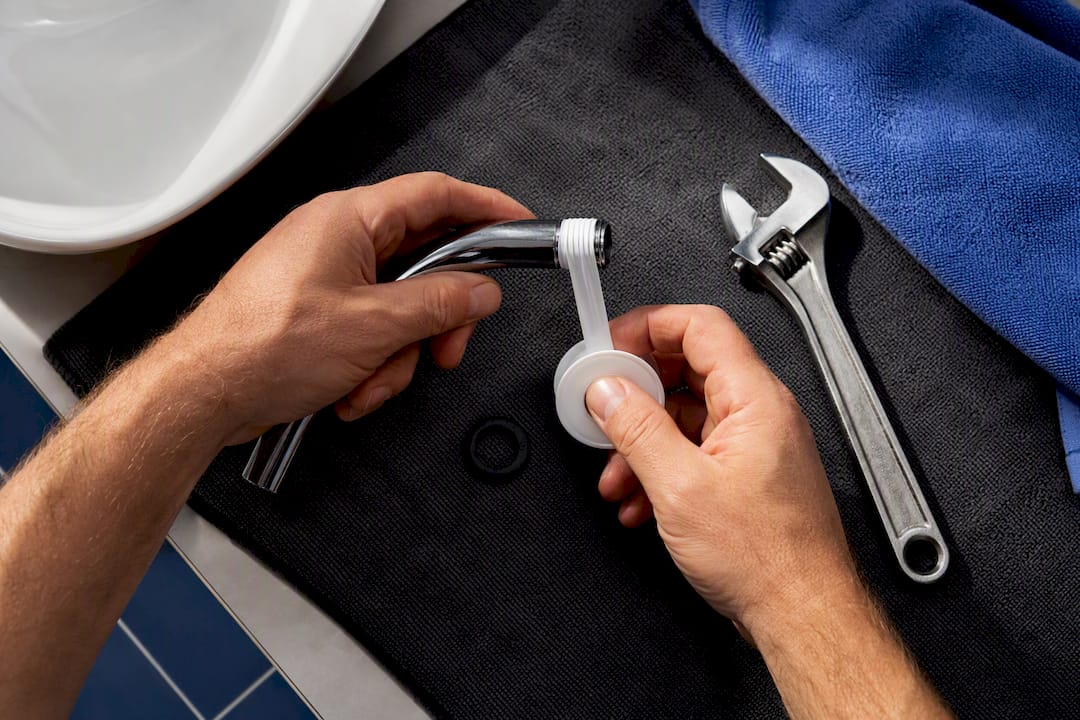 Plumber wrapping tape on shower thread