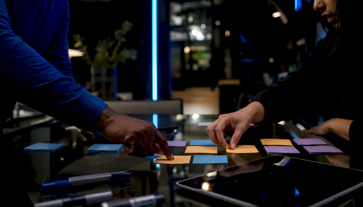 Hands arranging sticky notes during POC planning session