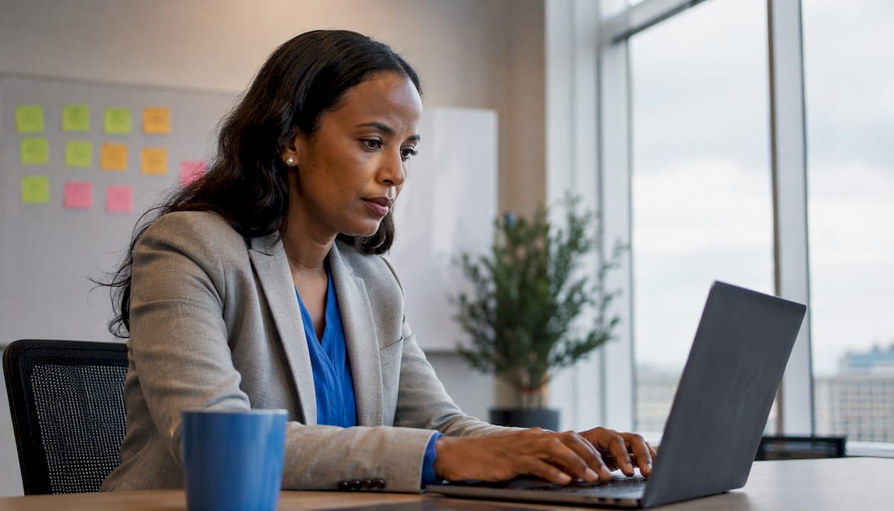 Woman typing contract review on laptop in site office