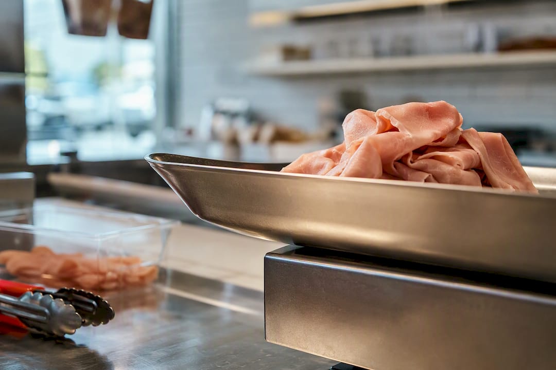 Deli goods beside cropped weighing pan