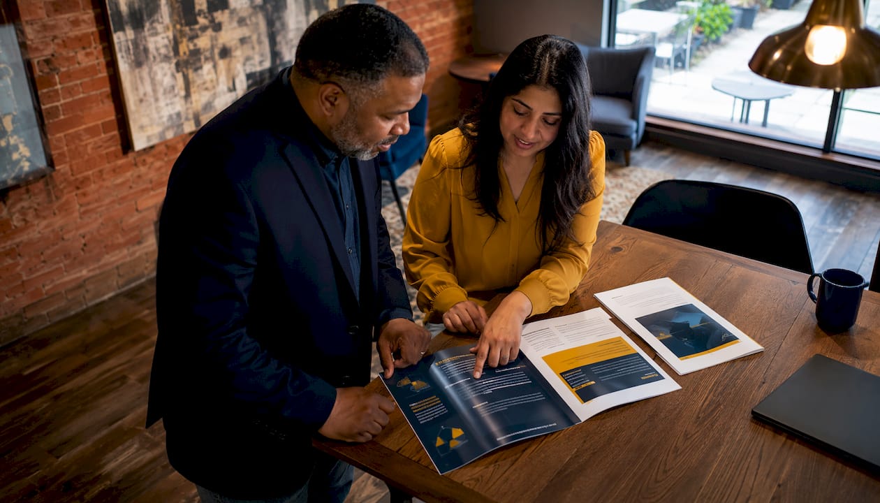 Two colleagues reviewing cybersecurity brochures in office lobby