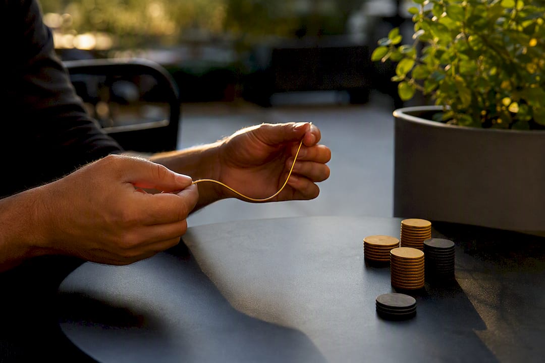 Hands bending a golden rod on dark desk