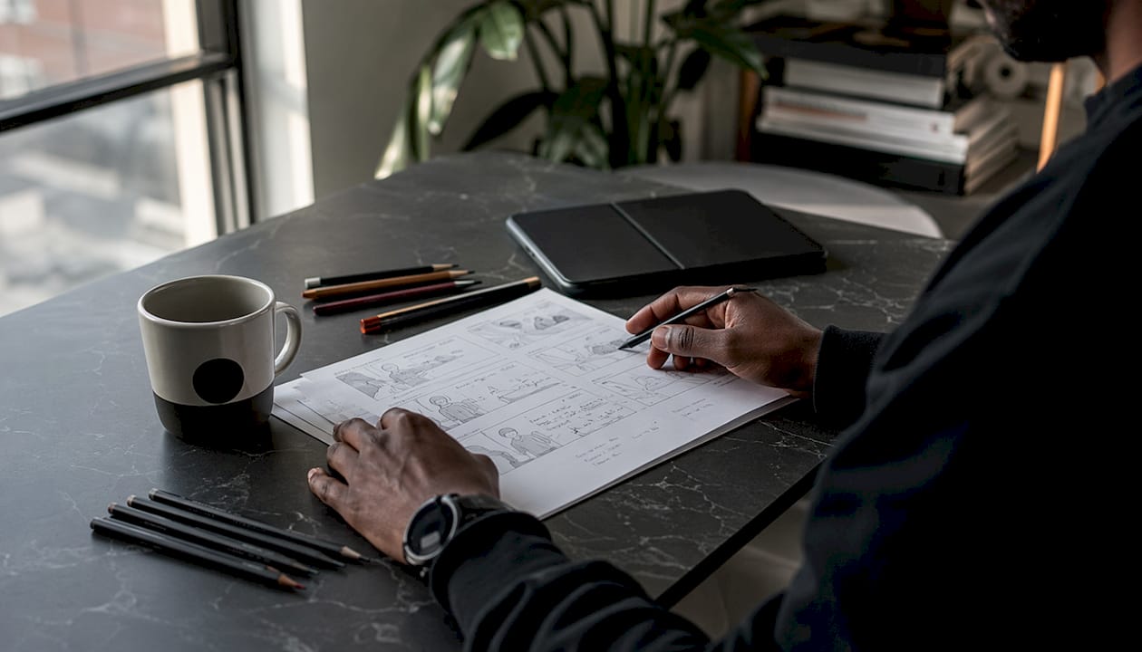 Hands pointing at storyboard panel details on desk