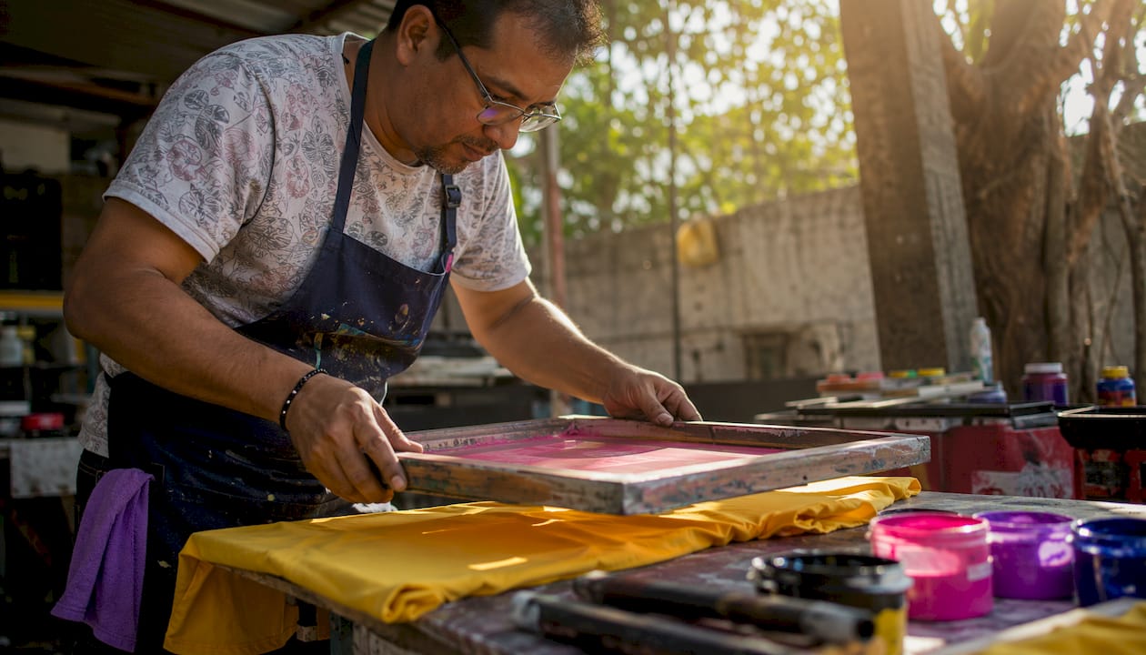 Man working on screen printing t-shirt in workshop