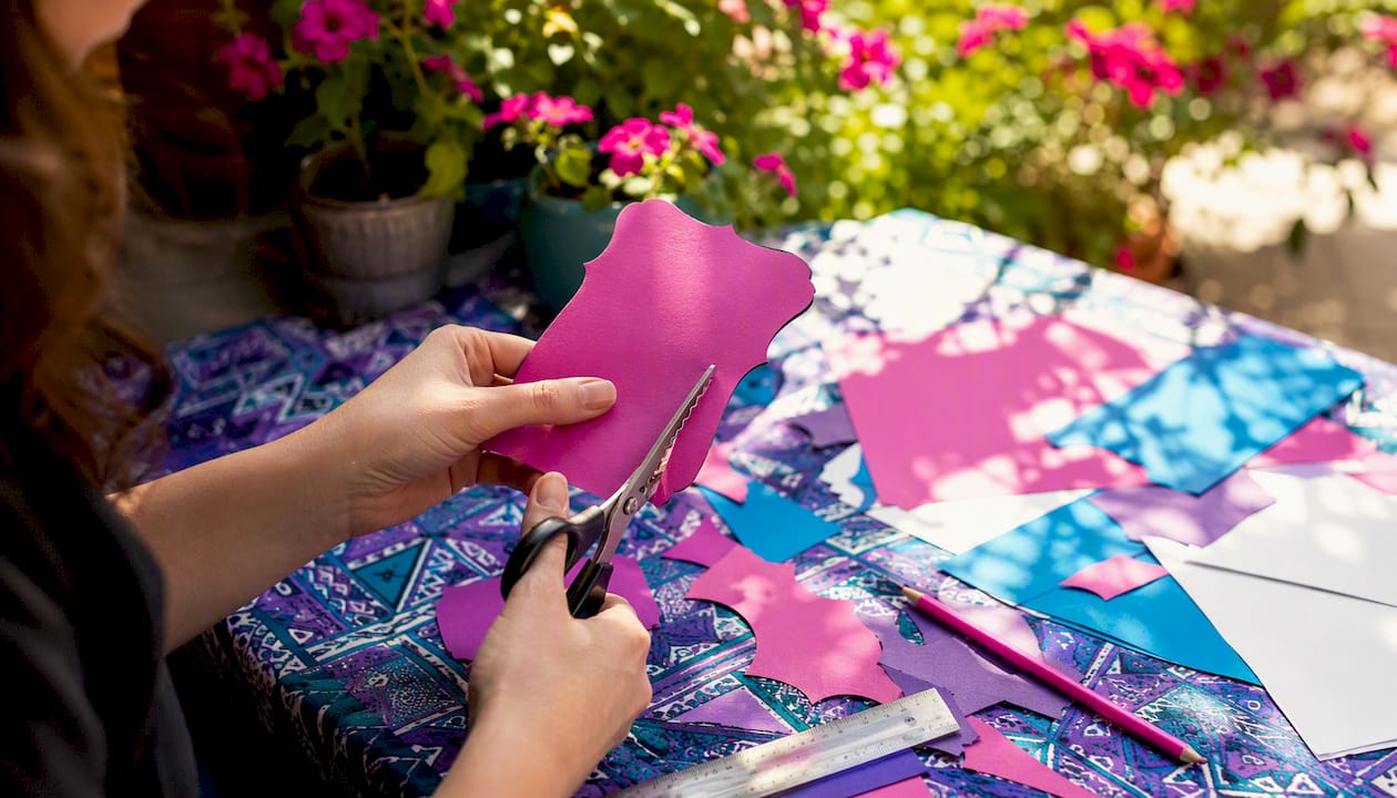 Hands cutting custom-shaped invitation prototype
