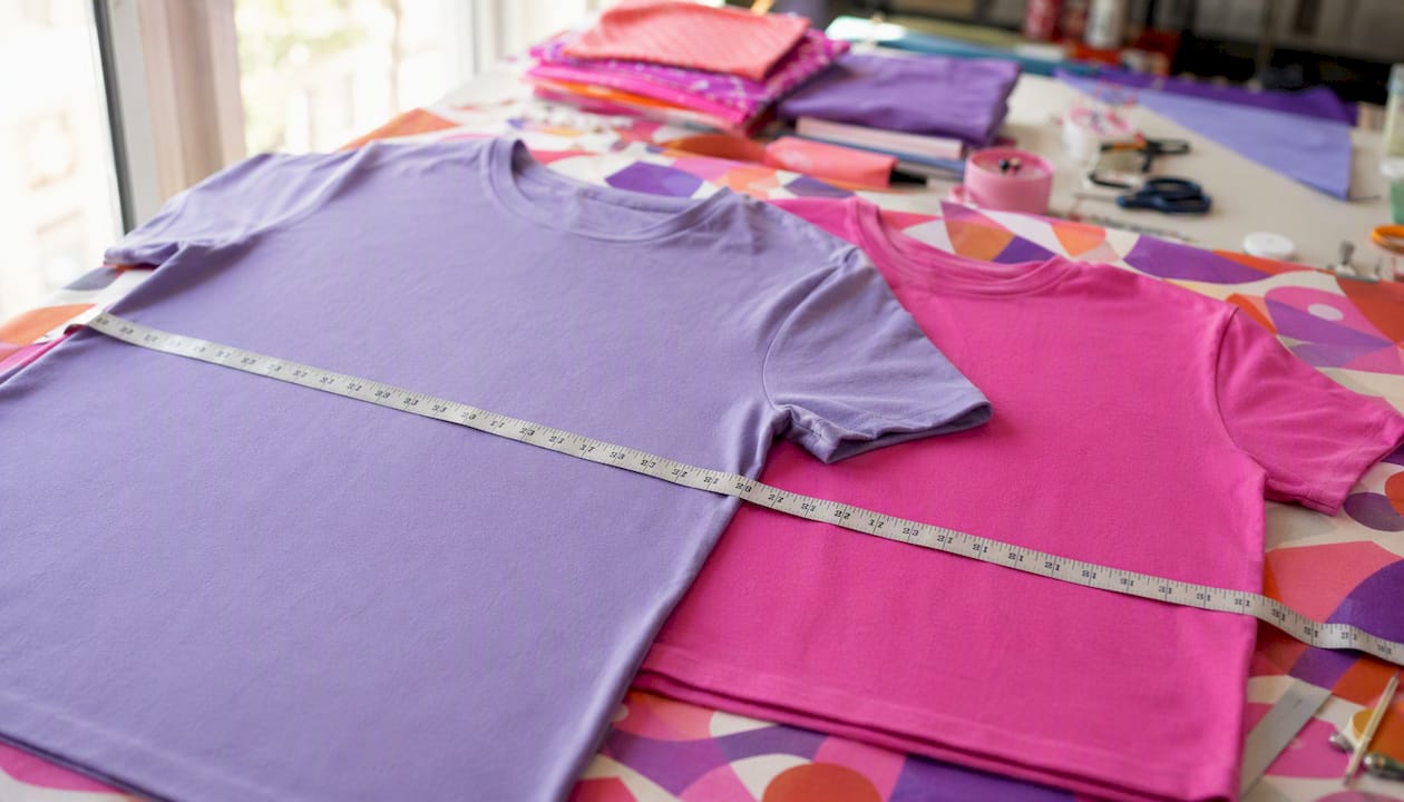 Partial youth and adult t-shirts laid flat with tape measure