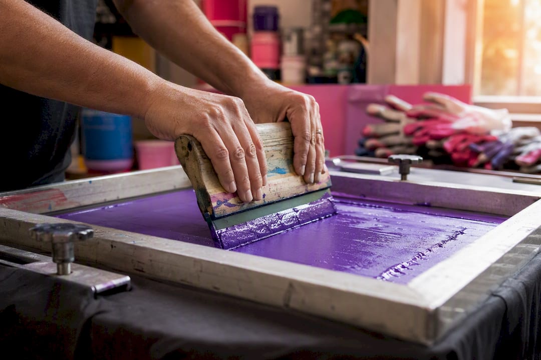 Hands applying plastisol ink to cotton t-shirt
