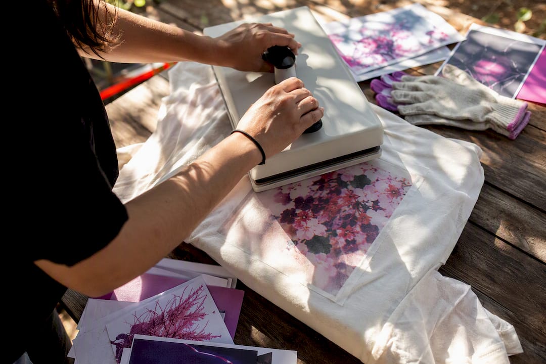 Hands applying DTF heat press transfer on dark shirt