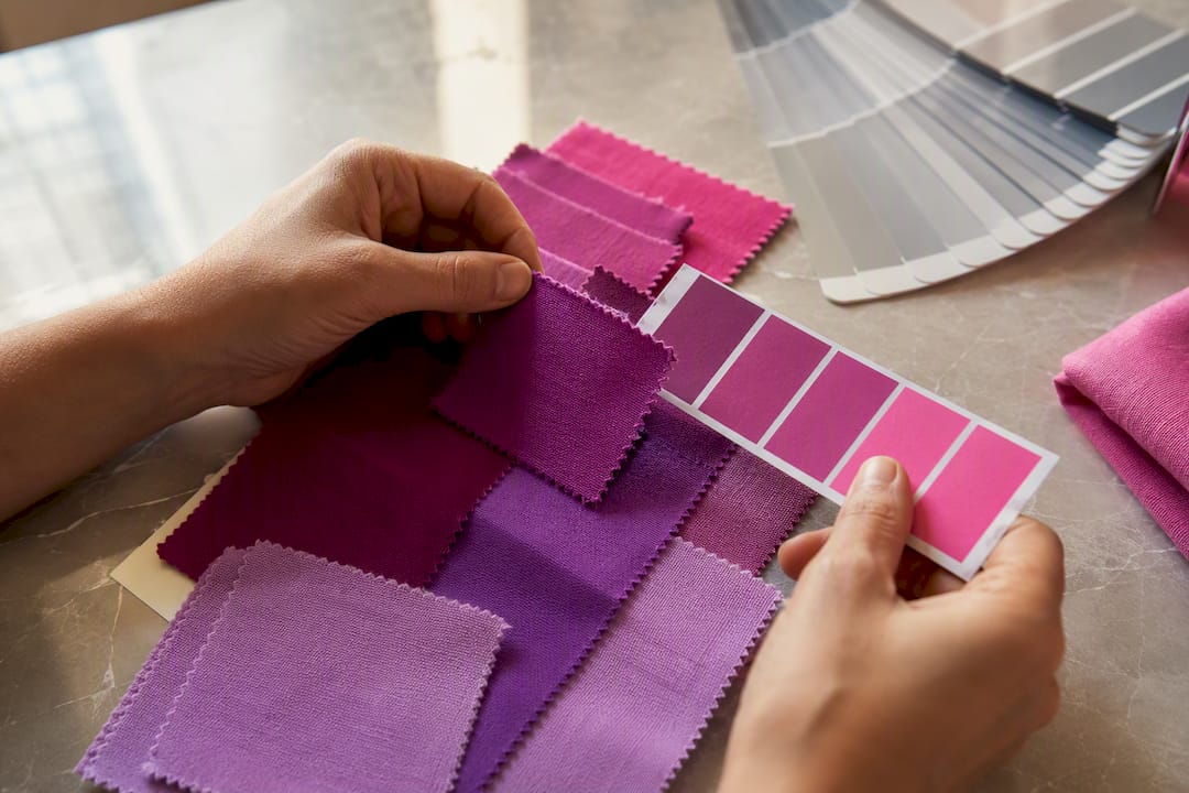 Hands comparing textile and paper color swatches