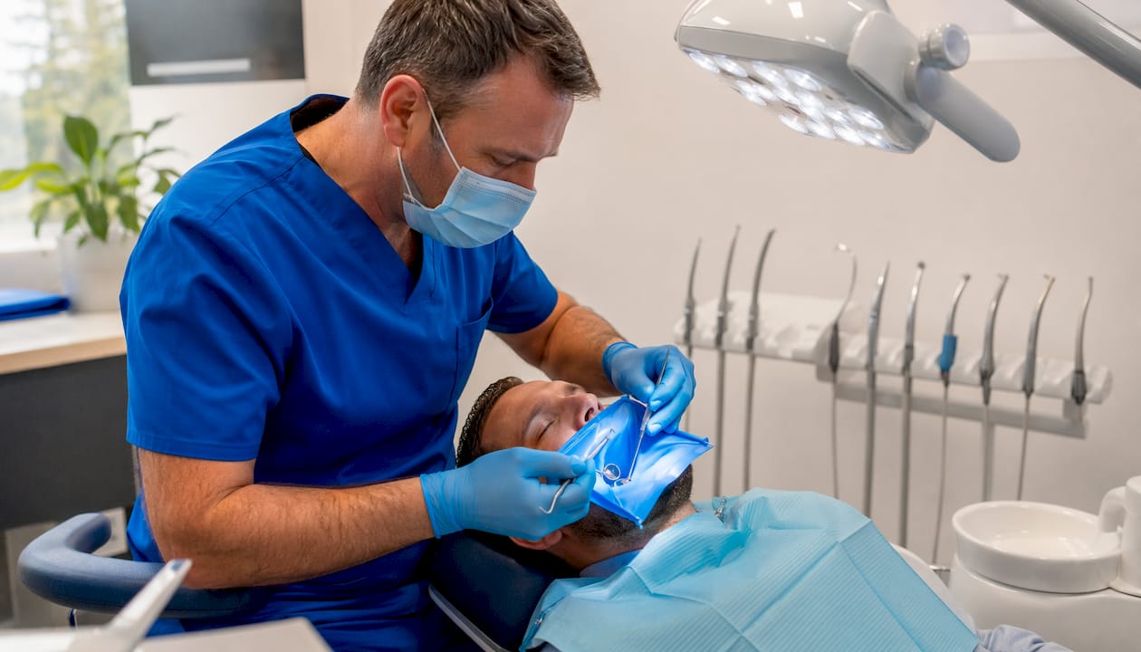 Dentist fitting crown on patient's tooth in clinic