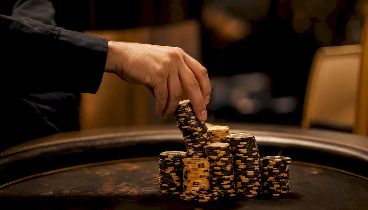 Dealer hand placing chips on poker table