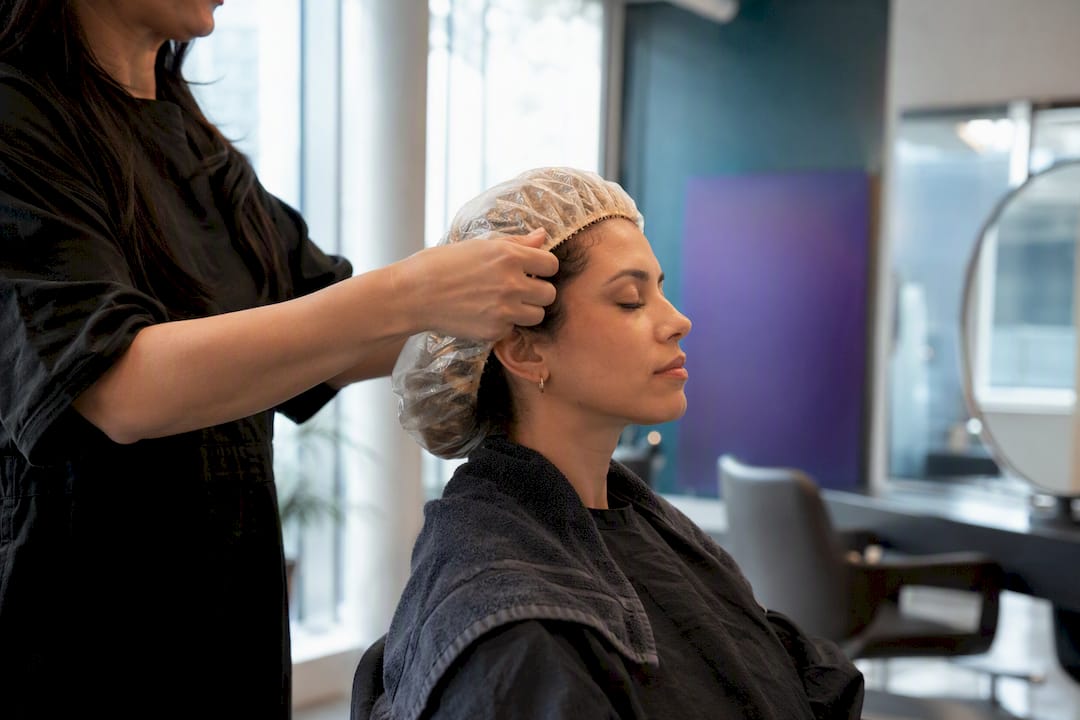Stylist placing shower cap for hair masque treatment