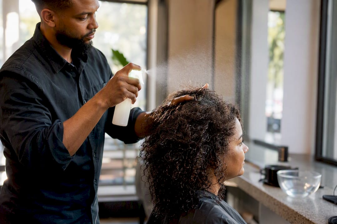 Stylist spraying moisture mist on high porosity hair