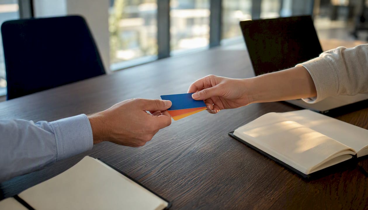 Hands exchanging contact cards representing SDR to AE handoff