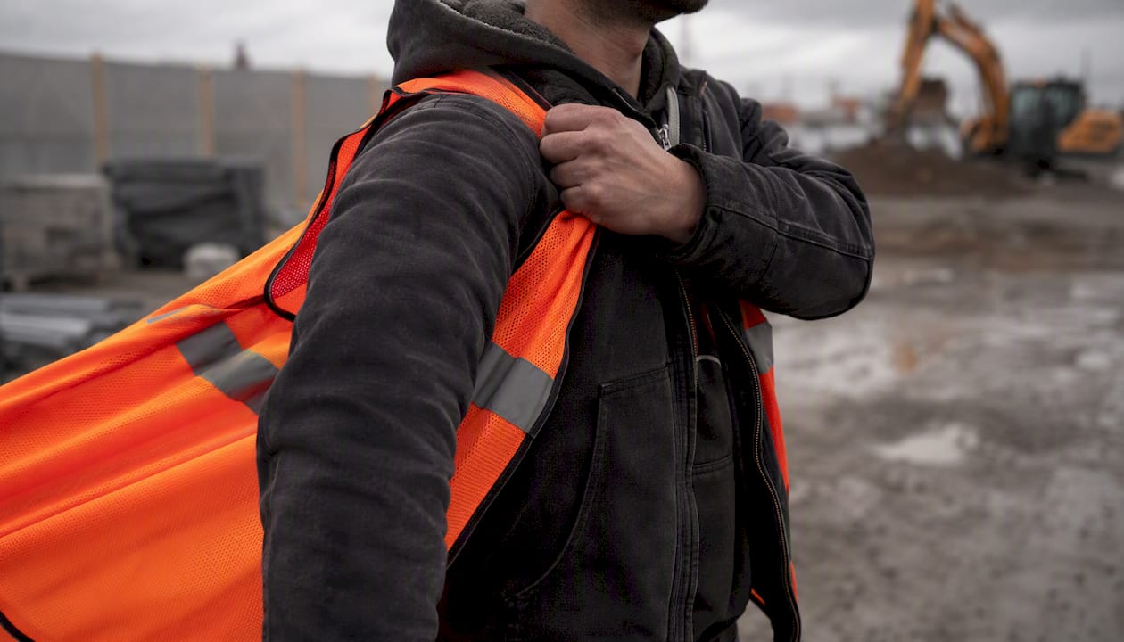 Worker pulling on safety vest outdoors