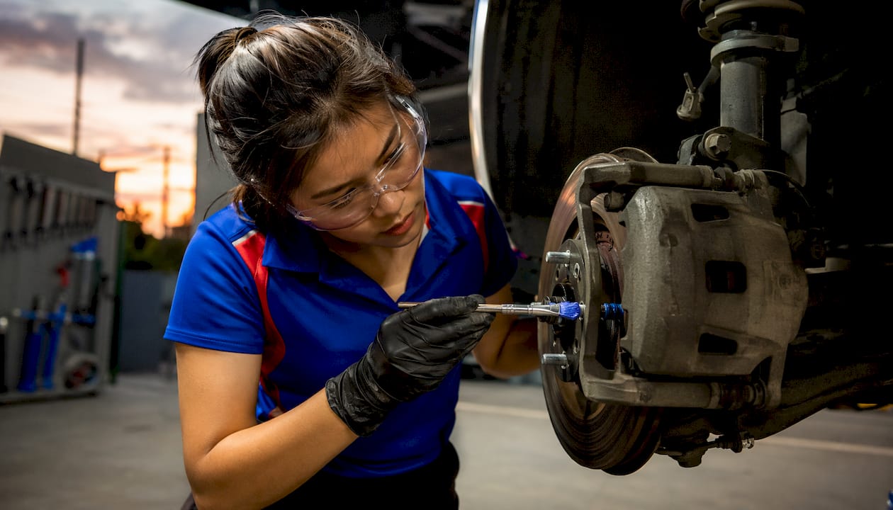 Technician lubricating brake caliper slide pins