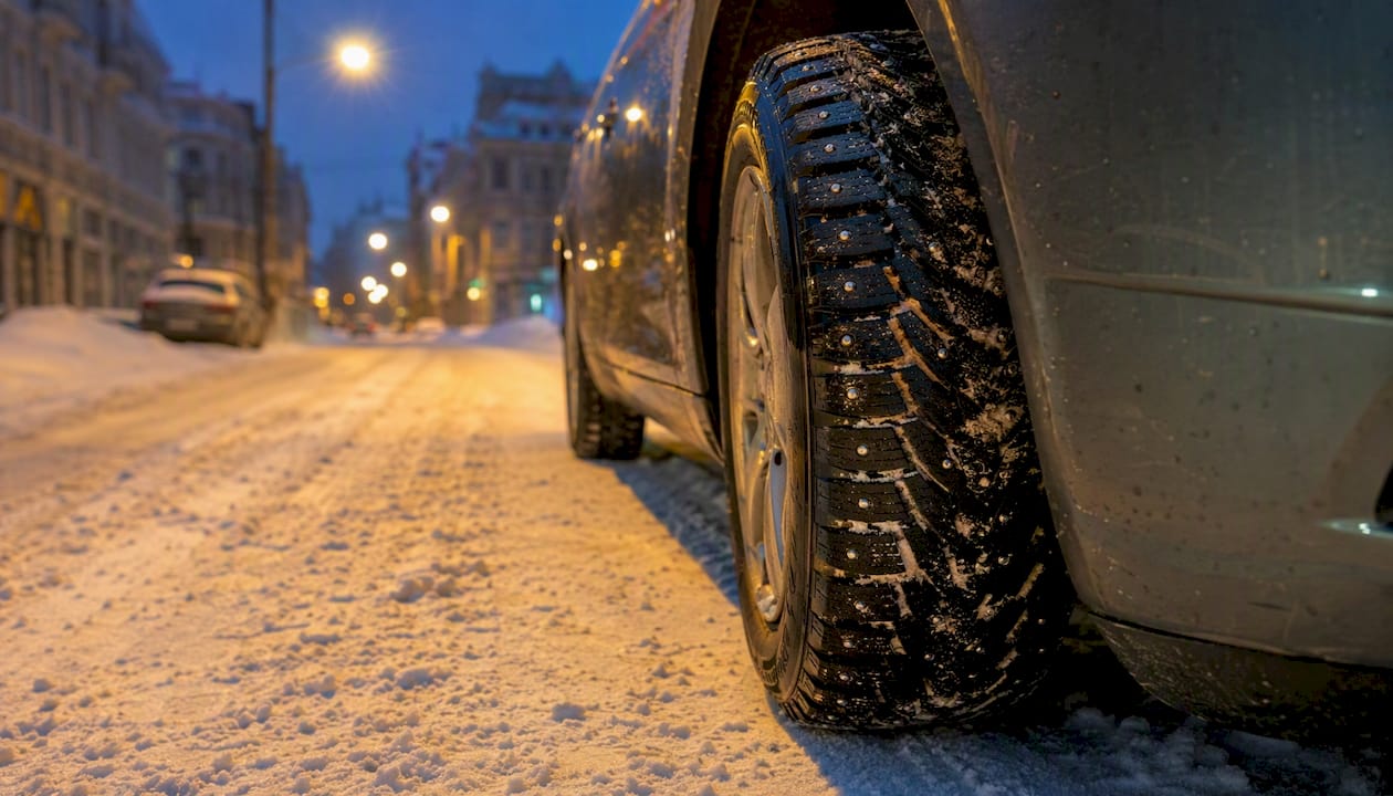 Close-up of studded winter tire on snowy road