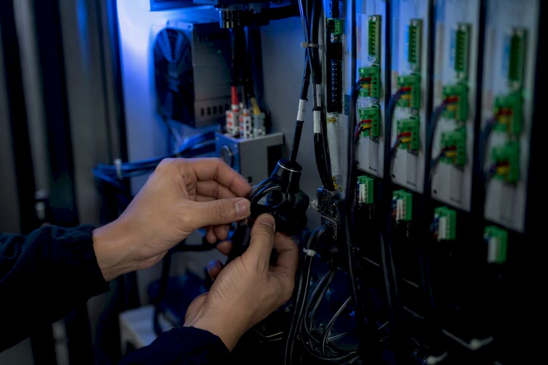 Technician adjusting wiring and sensors inside cnc cabinet