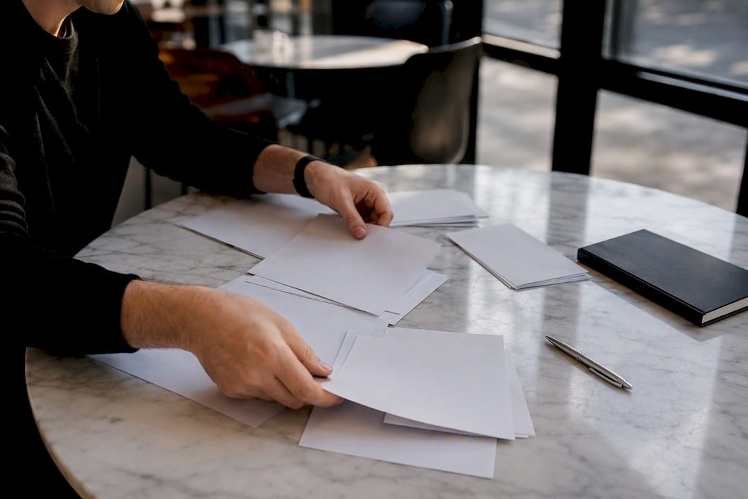 Hands arranging financial documents on black desk