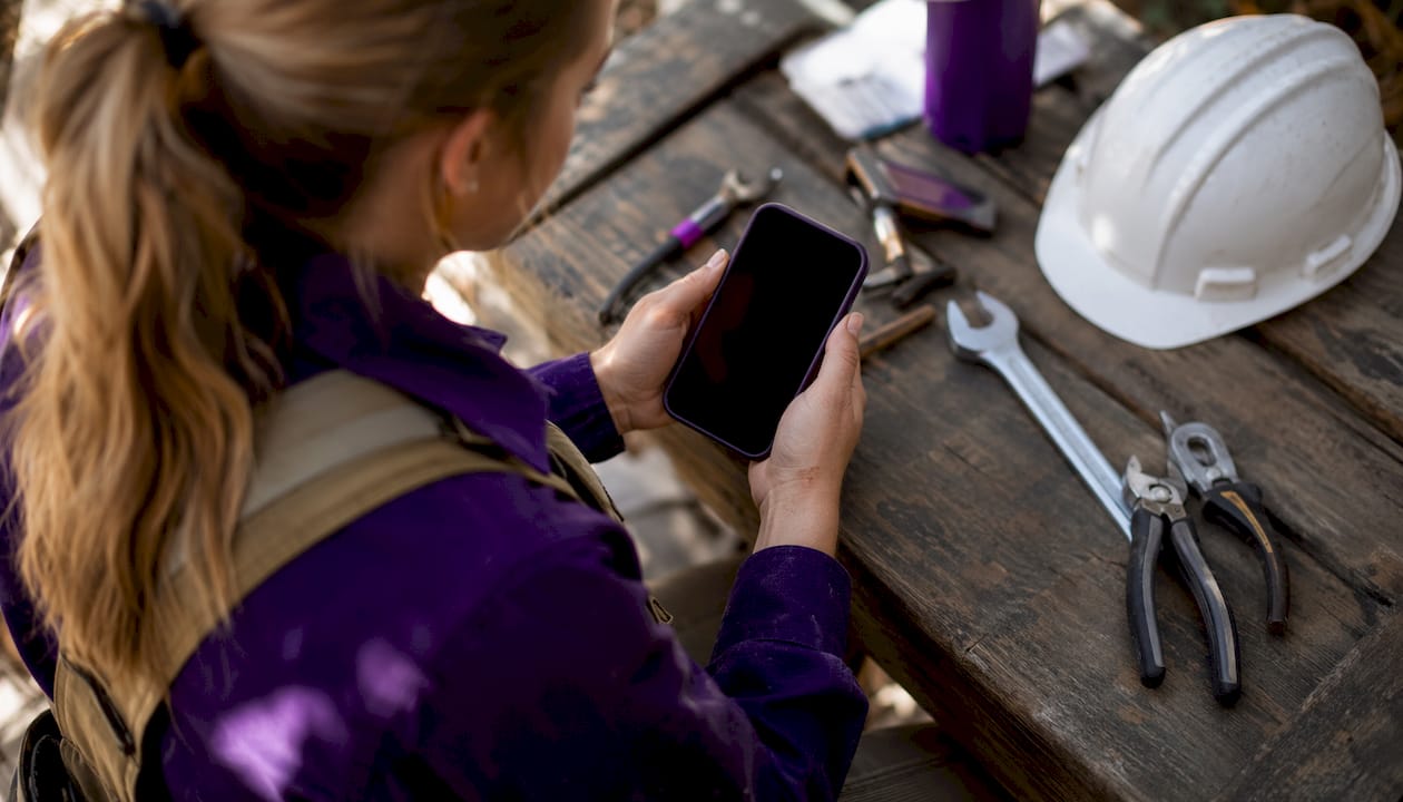 Hands holding smartphone over workbench tools